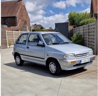 a small silver car parked in front of a house