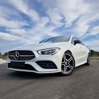 the white mercedes cla is parked on the road